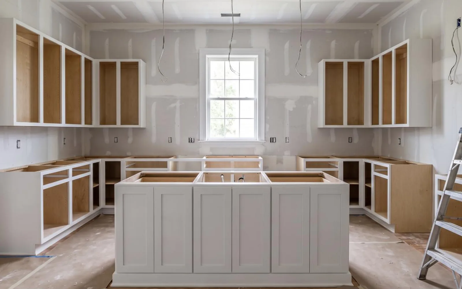 Kitchen with new drywall, plumbing rough-in and unfinished cabinet boxes installed